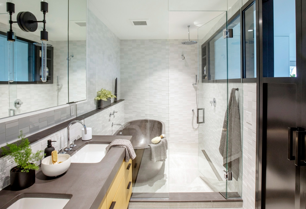 This is an example of a mid-sized contemporary master wet room bathroom in Vancouver with flat-panel cabinets, medium wood cabinets, a freestanding tub, white tile, mosaic tile, porcelain floors, an undermount sink, concrete benchtops, grey floor, a hinged shower door, grey benchtops and a double vanity.