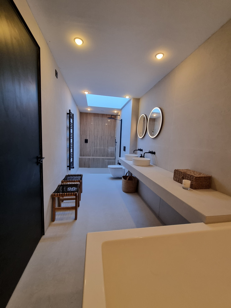 Inredning av ett nordiskt stort vit vitt en-suite badrum, med vita skåp, ett japanskt badkar, en öppen dusch, en vägghängd toalettstol, vit kakel, porslinskakel, vita väggar, klinkergolv i porslin, ett fristående handfat, kaklad bänkskiva och vitt golv