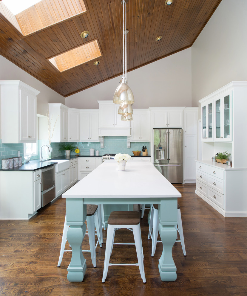 Design ideas for a traditional kitchen in Kansas City with a farmhouse sink, shaker cabinets, white cabinets, quartz benchtops, blue splashback, subway tile splashback, stainless steel appliances, dark hardwood floors and with island.