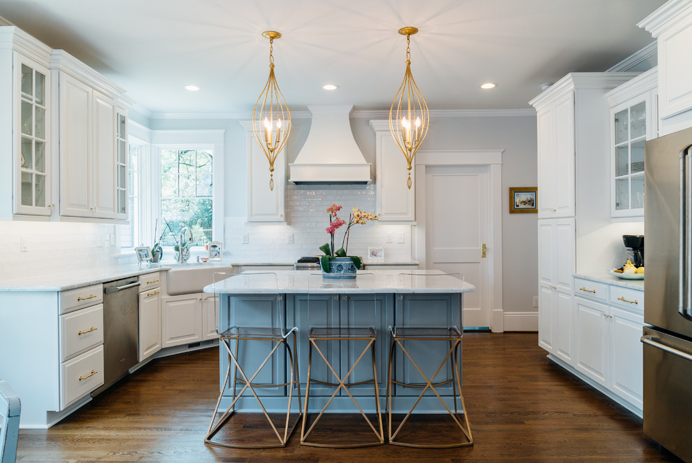 Inspiration for a traditional u-shaped eat-in kitchen in Raleigh with a farmhouse sink, raised-panel cabinets, blue cabinets, white splashback, stainless steel appliances, medium hardwood floors, with island, brown floor and white benchtop.