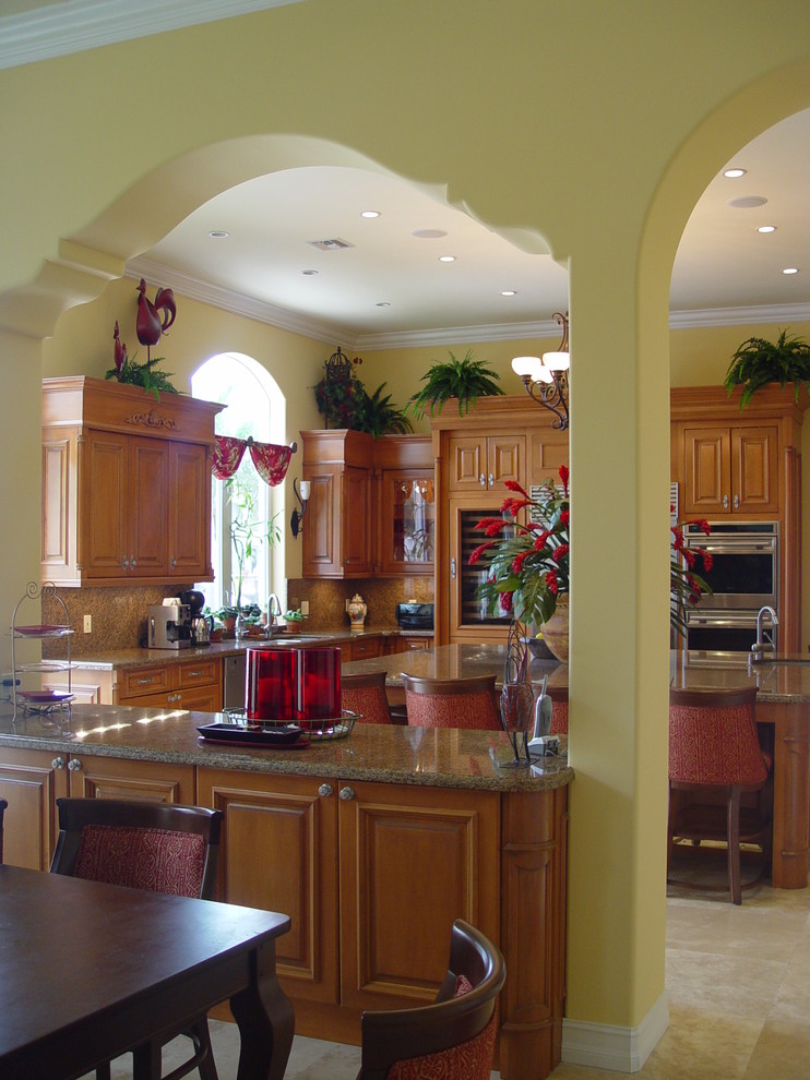 Photo of a mediterranean kitchen in Other with granite benchtops, raised-panel cabinets, medium wood cabinets and stainless steel appliances.