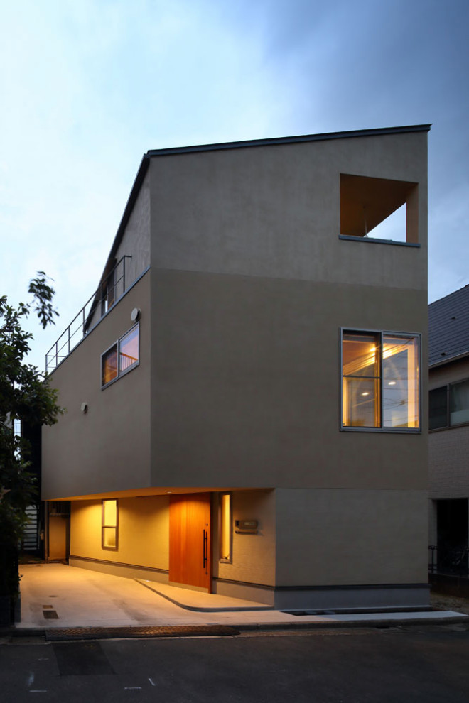 Kleines, Dreistöckiges Einfamilienhaus mit Putzfassade, beiger Fassadenfarbe, Pultdach, Blechdach und grauem Dach in Tokio