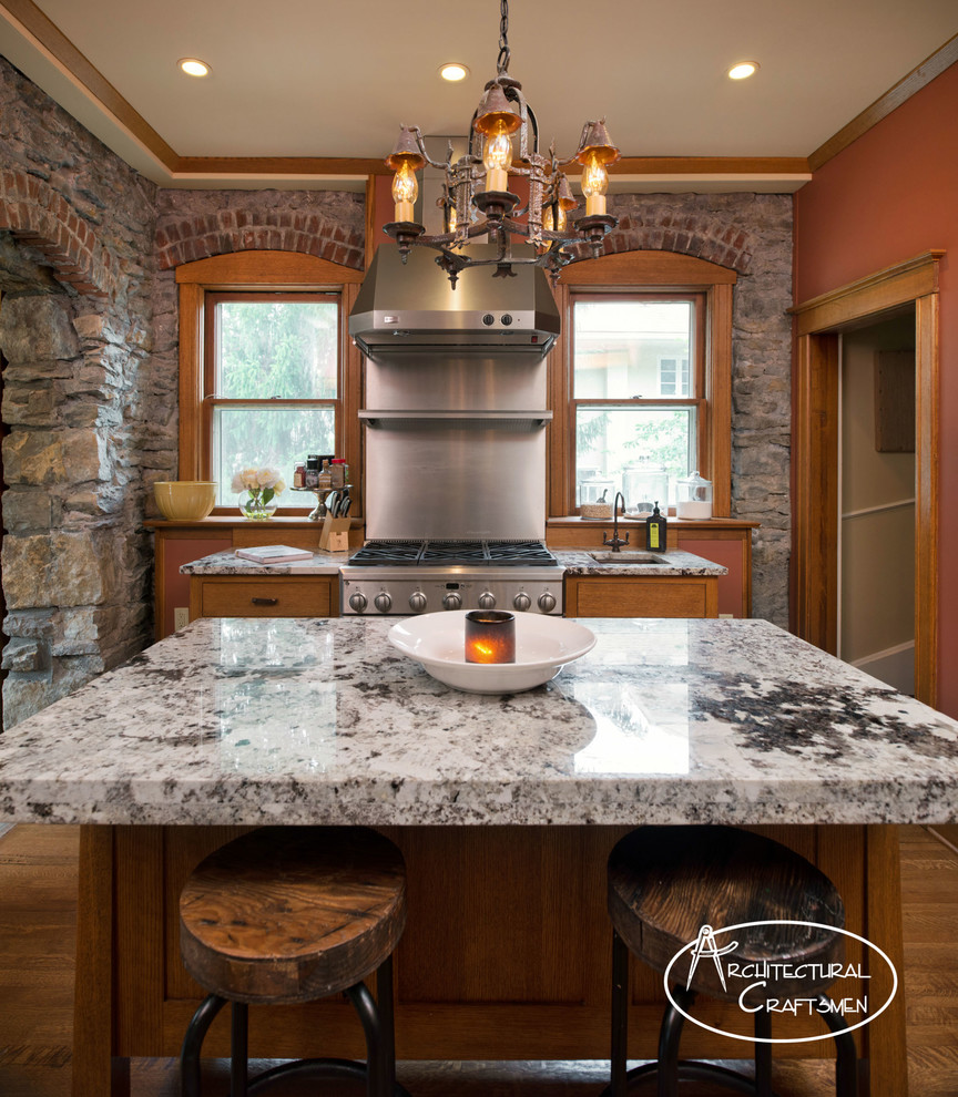 This is an example of a country kitchen in Kansas City with a farmhouse sink, shaker cabinets, medium wood cabinets, granite benchtops and panelled appliances.