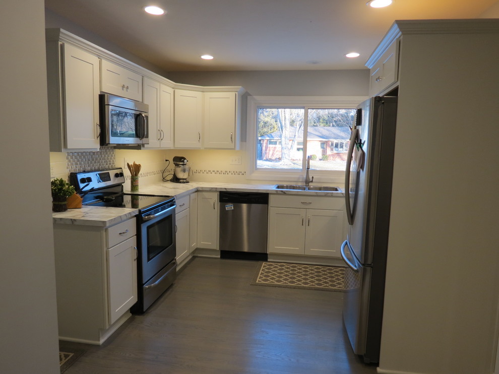 Inspiration for a mid-sized transitional u-shaped kitchen remodel with a drop-in sink, shaker cabinets, white cabinets, marble countertops, multicolored backsplash, porcelain backsplash and stainless steel appliances