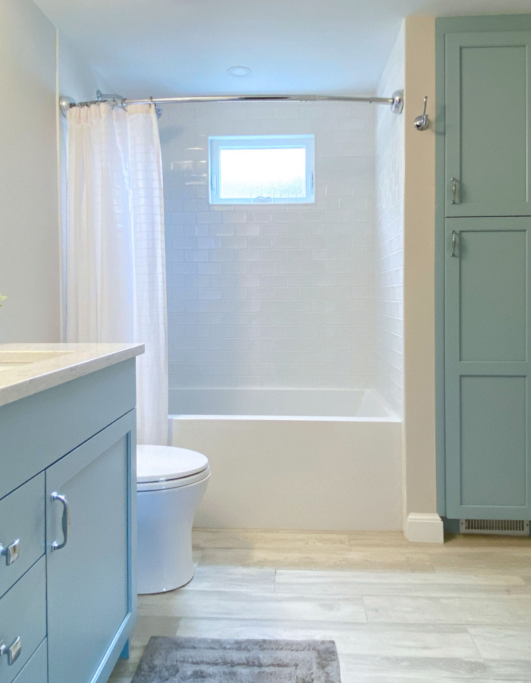 Cette photo montre une salle de bain chic avec un placard avec porte à panneau surélevé, des portes de placard bleues, un combiné douche/baignoire, WC séparés, un carrelage blanc, des carreaux de céramique, un mur blanc, un sol en carrelage de porcelaine, un lavabo encastré, un plan de toilette en quartz modifié, un sol beige, une cabine de douche avec un rideau, un plan de toilette blanc, meuble simple vasque et meuble-lavabo encastré.
