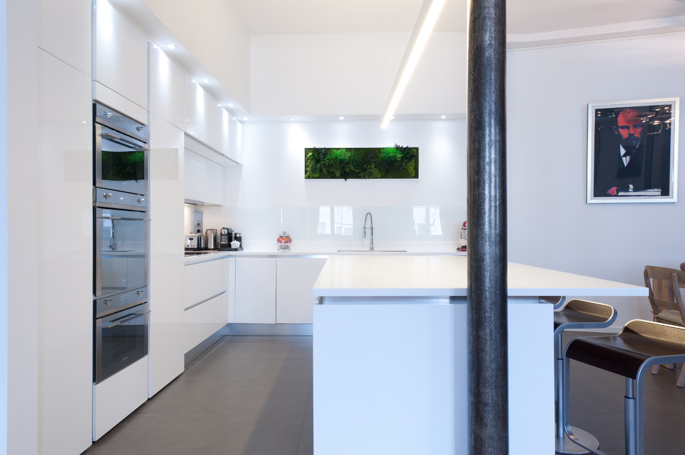 This is an example of a mid-sized modern l-shaped eat-in kitchen in Paris with an integrated sink, beaded inset cabinets, white cabinets, quartzite benchtops, white splashback, glass tile splashback, panelled appliances, terra-cotta floors and with island.