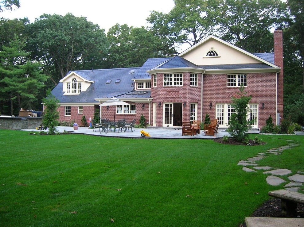 Mid-sized traditional two-storey brick red house exterior in Huntington with a gable roof and a shingle roof.