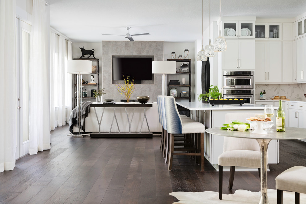 Inspiration for a mid-sized transitional l-shaped dark wood floor and brown floor eat-in kitchen remodel in Orlando with an undermount sink, shaker cabinets, white cabinets, solid surface countertops, white backsplash, stone slab backsplash, stainless steel appliances, an island and white countertops