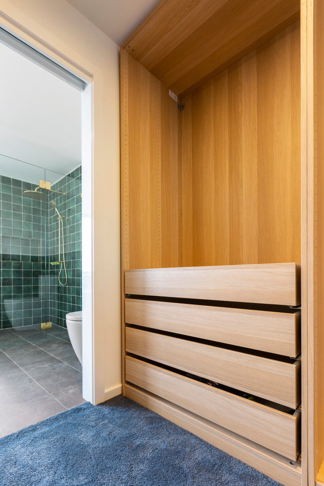 Photo of a medium sized contemporary gender neutral walk-in wardrobe in Canberra - Queanbeyan with open cabinets, medium wood cabinets, carpet and blue floors.
