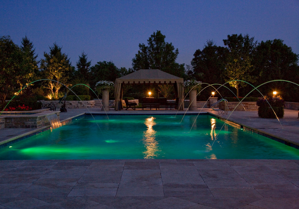 Design ideas for a large traditional backyard rectangular lap pool in Chicago with a hot tub and natural stone pavers.