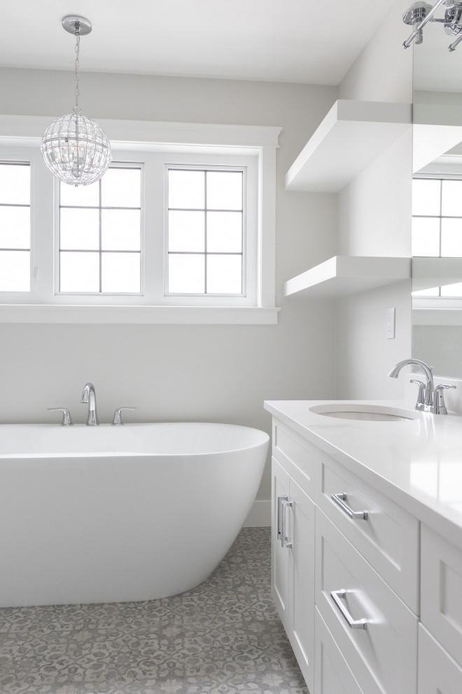 This is an example of a mid-sized country master bathroom in Other with shaker cabinets, white cabinets, a freestanding tub, a one-piece toilet, white walls, an undermount sink, grey floor, a hinged shower door, white benchtops and an alcove shower.