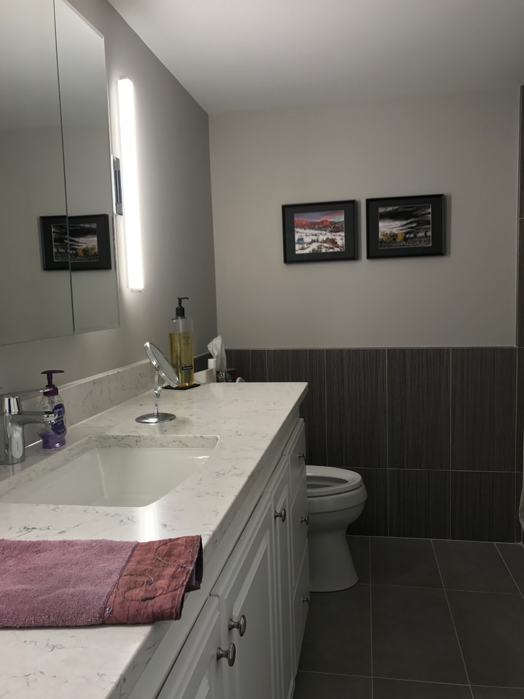 Inspiration for a mid-sized transitional 3/4 black tile and porcelain tile laminate floor and black floor alcove shower remodel with raised-panel cabinets, white cabinets, a two-piece toilet, gray walls, an undermount sink, marble countertops and white countertops