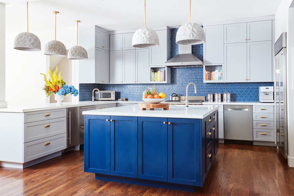 This is an example of a large eclectic l-shaped open plan kitchen in San Francisco with an undermount sink, shaker cabinets, blue cabinets, quartz benchtops, blue splashback, ceramic splashback, stainless steel appliances, medium hardwood floors, with island and white benchtop.