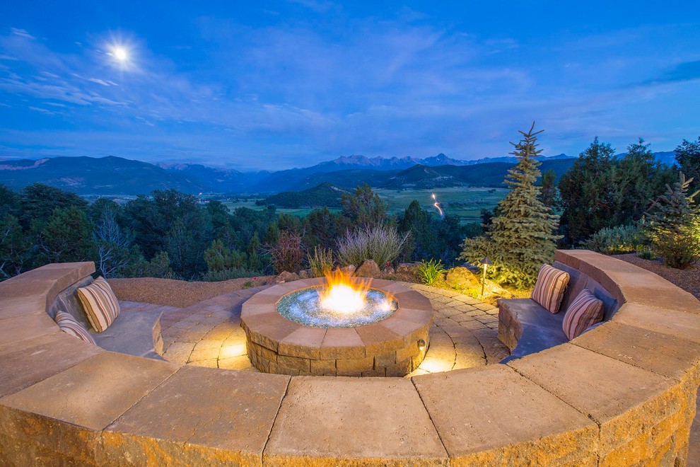 Photo of a large country backyard patio in Denver with a fire feature, natural stone pavers and no cover.