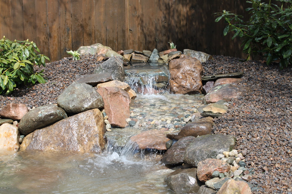 Photo of a mid-sized traditional backyard partial sun garden for summer in Detroit with a water feature and gravel.