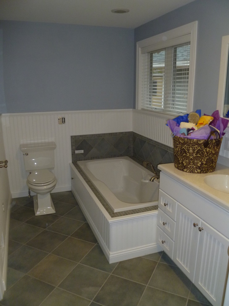 Inspiration for a small timeless 3/4 gray tile and ceramic tile ceramic tile drop-in bathtub remodel in Boston with shaker cabinets, white cabinets, a two-piece toilet, blue walls, an integrated sink and laminate countertops