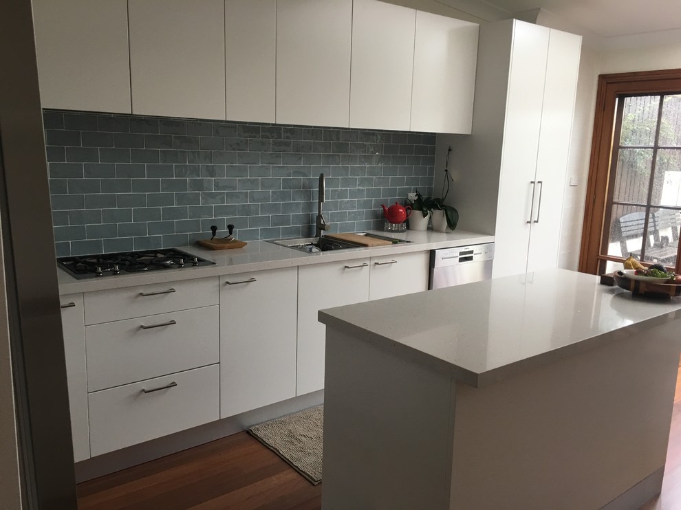 Photo of a contemporary kitchen pantry in Sydney with a double-bowl sink, white cabinets, grey splashback, subway tile splashback, stainless steel appliances, medium hardwood floors and with island.