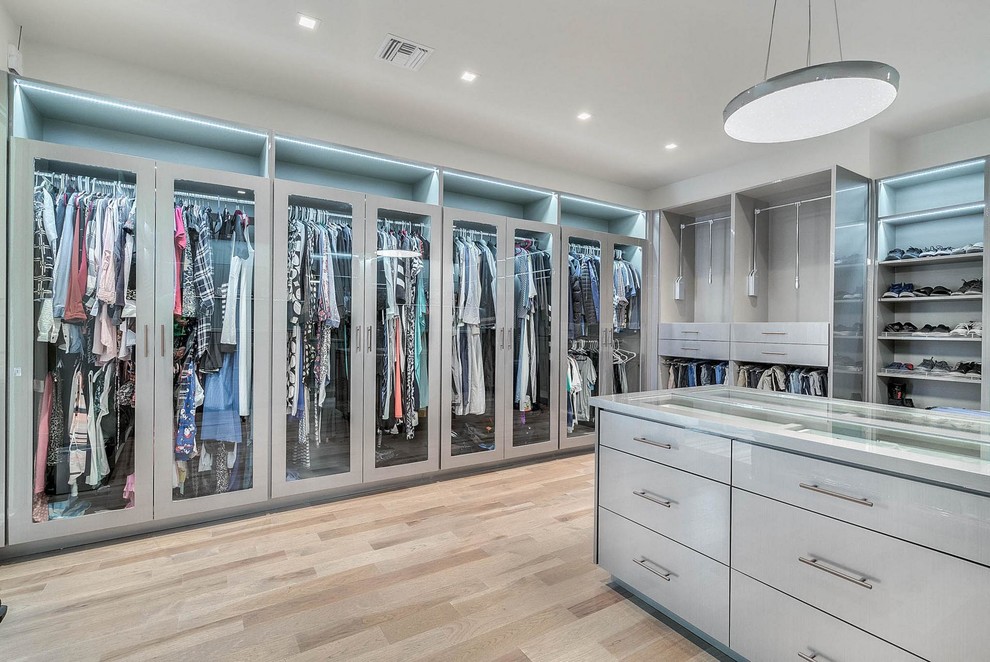 Large contemporary women's walk-in wardrobe in Orlando with glass-front cabinets, grey cabinets, light hardwood floors and beige floor.