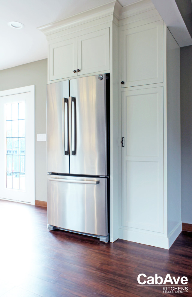 Inspiration for a mid-sized transitional l-shaped vinyl floor and brown floor eat-in kitchen remodel with an undermount sink, recessed-panel cabinets, white cabinets, quartz countertops, beige backsplash, ceramic backsplash, stainless steel appliances and no island