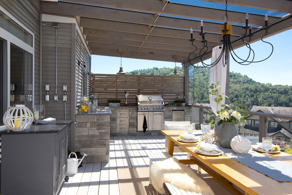 Example of a large transitional backyard outdoor kitchen deck design in Vancouver with a pergola