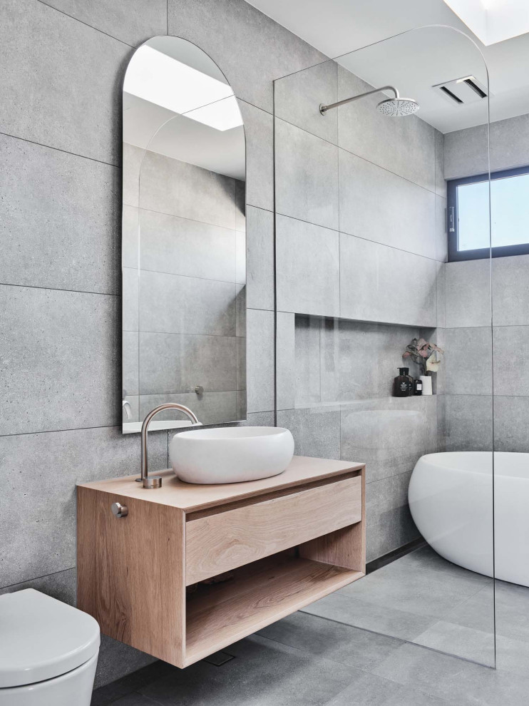 Photo of a contemporary wet room bathroom in Other with flat-panel cabinets, light wood cabinets, a freestanding tub, gray tile, a vessel sink, wood benchtops, grey floor, beige benchtops, a single vanity and a floating vanity.