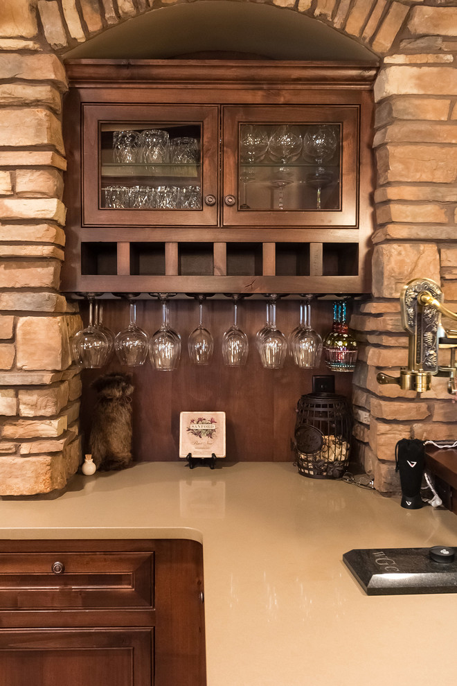 Inspiration for a mid-sized traditional u-shaped seated home bar in Minneapolis with an undermount sink, recessed-panel cabinets, dark wood cabinets, quartz benchtops, brown splashback, timber splashback, porcelain floors, beige floor and beige benchtop.