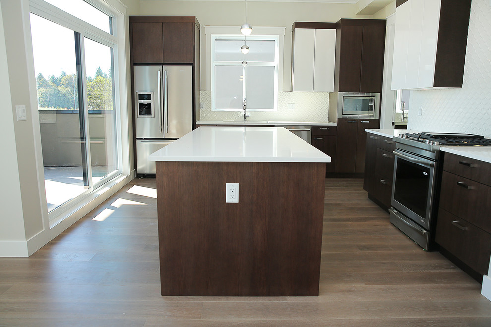 Example of a mid-sized transitional l-shaped dark wood floor and brown floor eat-in kitchen design in Orange County with an undermount sink, flat-panel cabinets, dark wood cabinets, solid surface countertops, white backsplash, porcelain backsplash, stainless steel appliances and an island