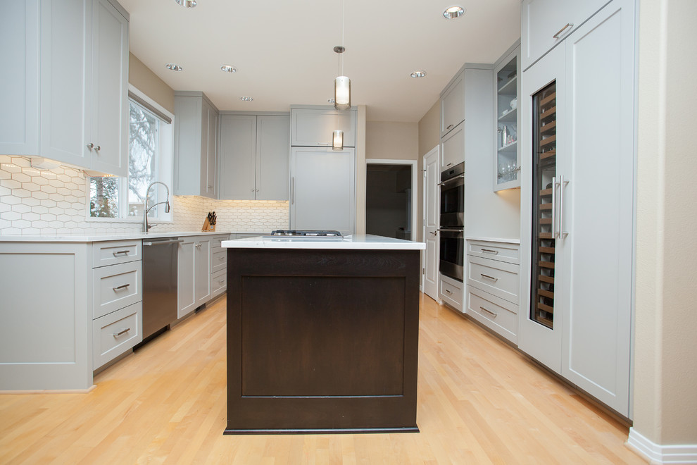 Design ideas for a mid-sized contemporary u-shaped eat-in kitchen in Portland with shaker cabinets, grey cabinets, white splashback, with island, an undermount sink, panelled appliances, light hardwood floors, brown floor and white benchtop.