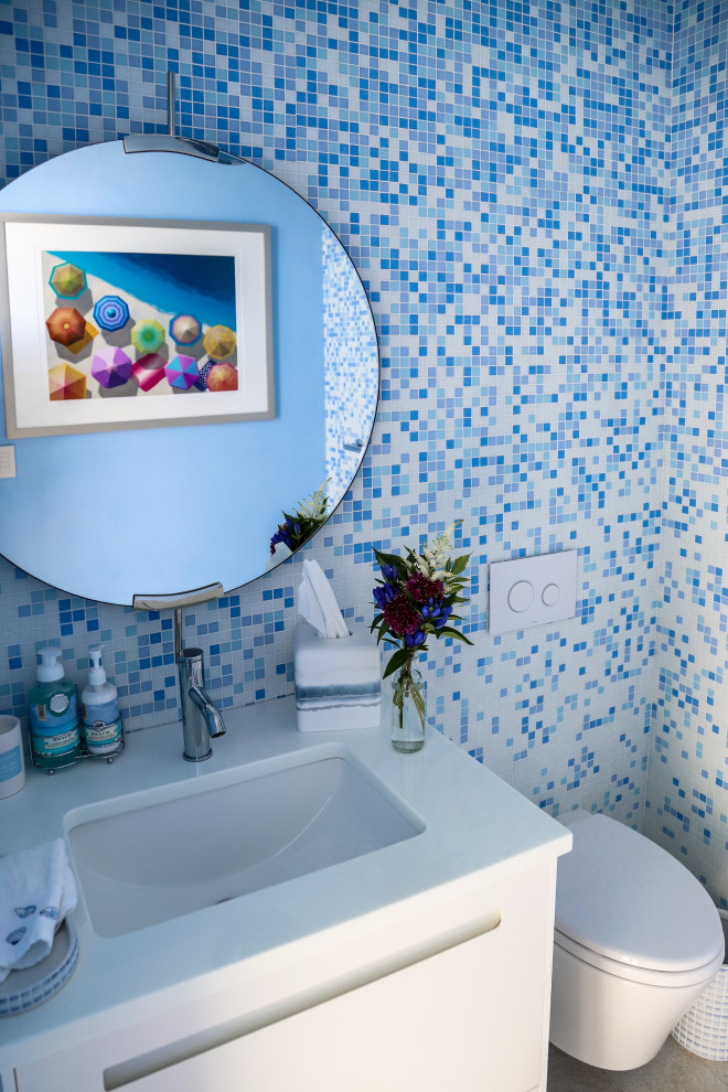 На фото: туалет среднего размера в морском стиле с белыми фасадами, унитазом-моноблоком, врезной раковиной, столешницей из искусственного кварца, белой столешницей и плиткой мозаикой с