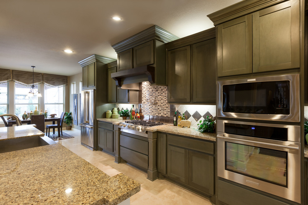 Inspiration for a mid-sized transitional galley travertine floor open concept kitchen remodel in Houston with a drop-in sink, shaker cabinets, green cabinets, granite countertops, white backsplash, subway tile backsplash, stainless steel appliances and an island