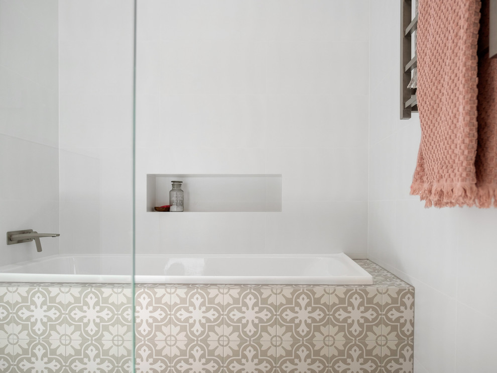 This is an example of a mediterranean bathroom in Perth with a drop-in tub, beige tile, white tile and white walls.