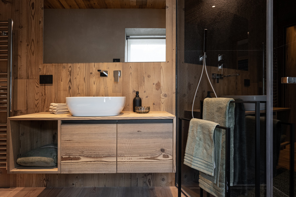 Пример оригинального дизайна: ванная комната в стиле рустика с открытыми фасадами, темными деревянными фасадами, угловым душем, коричневой плиткой, темным паркетным полом, душевой кабиной, настольной раковиной, столешницей из дерева, душем с раздвижными дверями, коричневой столешницей, тумбой под одну раковину, подвесной тумбой, деревянным потолком и деревянными стенами
