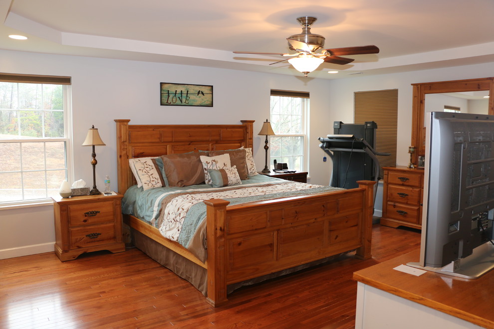Large traditional master bedroom in Other with grey walls and dark hardwood floors.