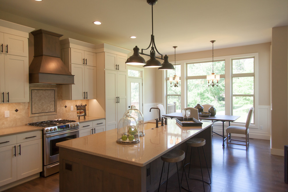 Inspiration for a large transitional l-shaped medium tone wood floor open concept kitchen remodel in Cedar Rapids with an undermount sink, shaker cabinets, white cabinets, quartz countertops, brown backsplash, stone tile backsplash, stainless steel appliances and an island