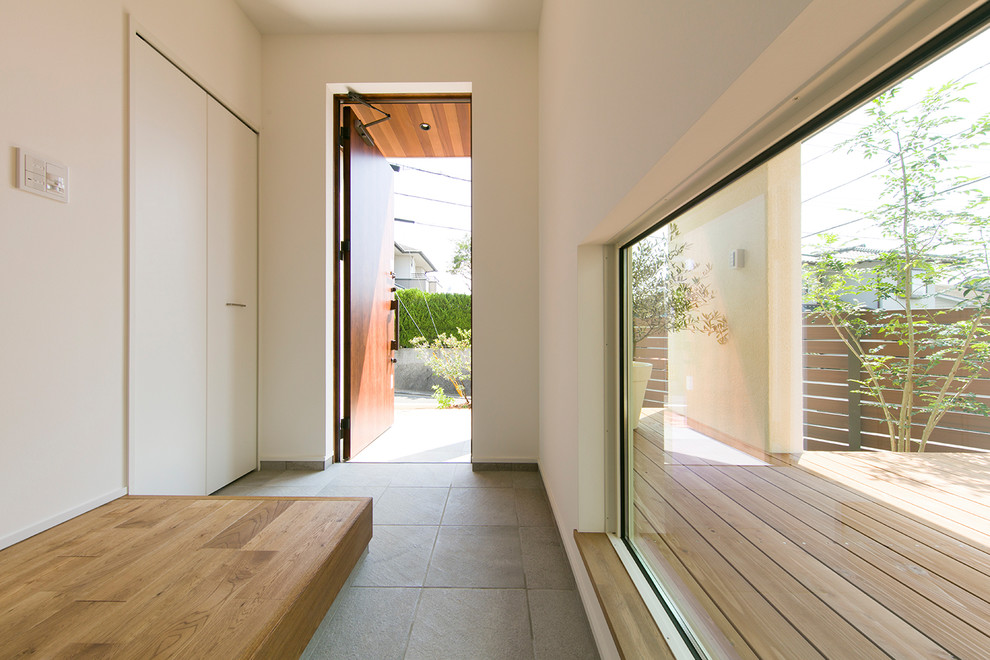 This is an example of an asian entry hall in Other with white walls, a single front door, a medium wood front door and grey floor.