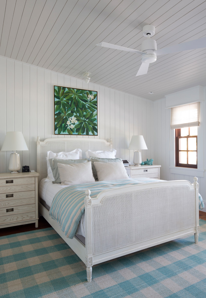 This is an example of a tropical guest bedroom in Hawaii with white walls, medium hardwood floors, no fireplace and brown floor.