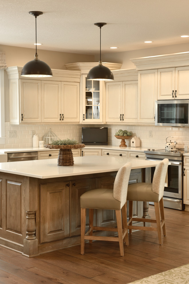Example of a large transitional u-shaped light wood floor eat-in kitchen design with a drop-in sink, flat-panel cabinets, white cabinets, laminate countertops, white backsplash, subway tile backsplash, stainless steel appliances and an island