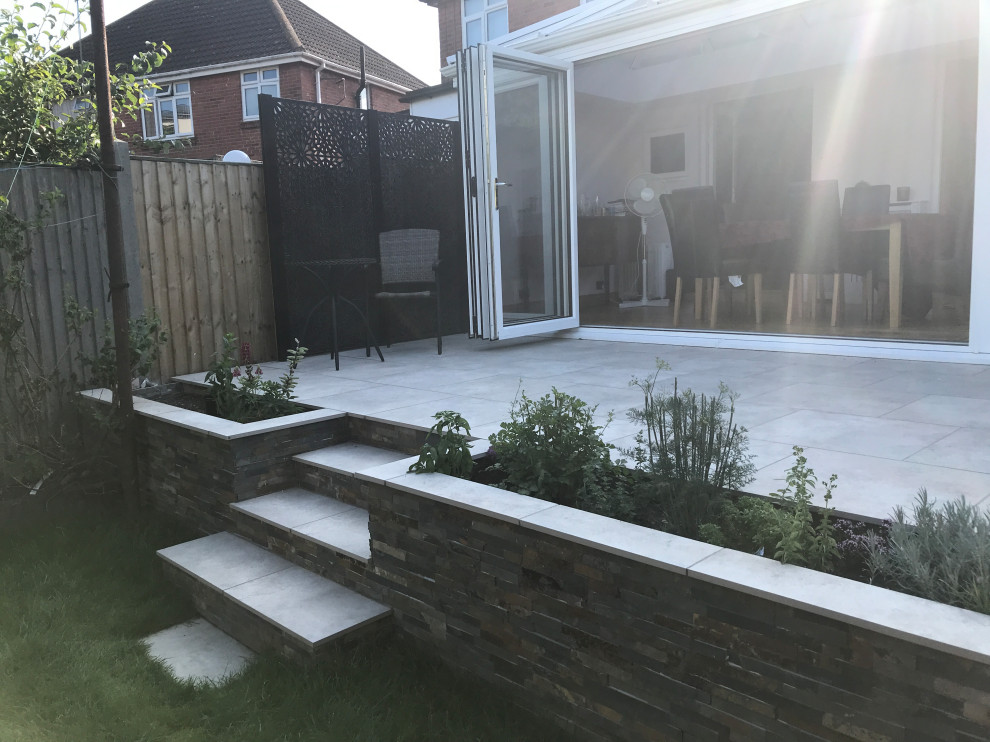 Design ideas for a small contemporary backyard partial sun formal garden in Hampshire with a retaining wall.