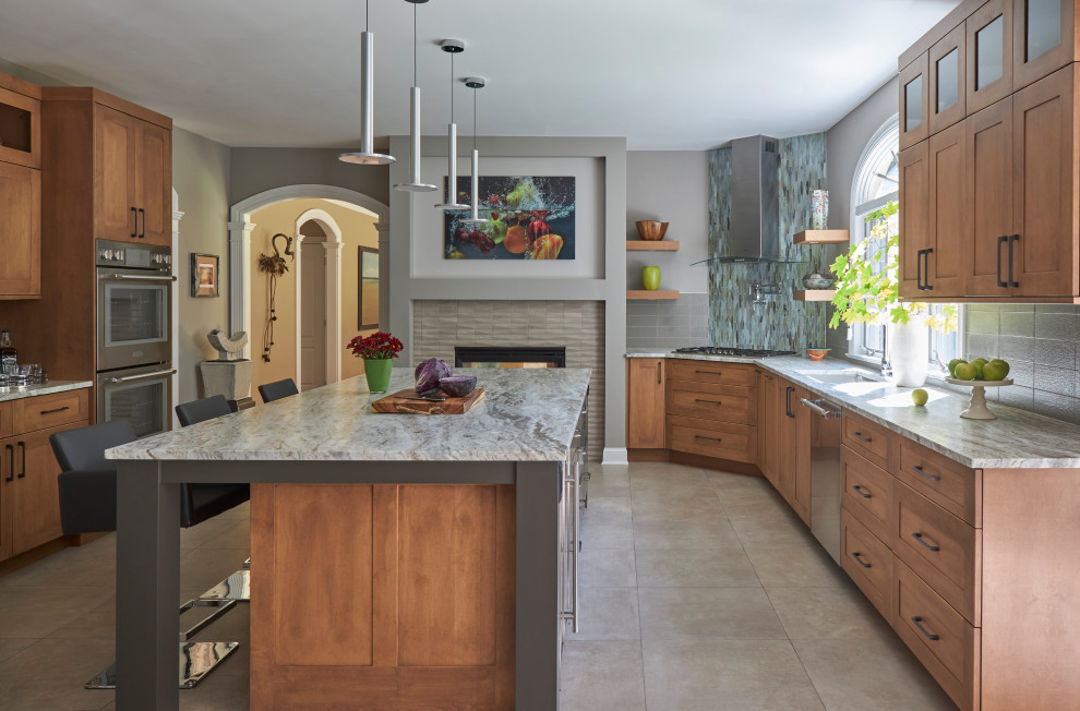 This is an example of a transitional u-shaped kitchen in New York with an undermount sink, shaker cabinets, medium wood cabinets, grey splashback, stainless steel appliances, with island, grey floor and grey benchtop.
