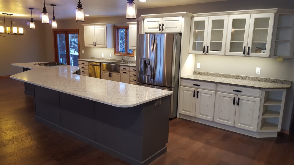 Open concept kitchen - large transitional galley medium tone wood floor open concept kitchen idea with a farmhouse sink, raised-panel cabinets, white cabinets, quartz countertops, stainless steel appliances and an island