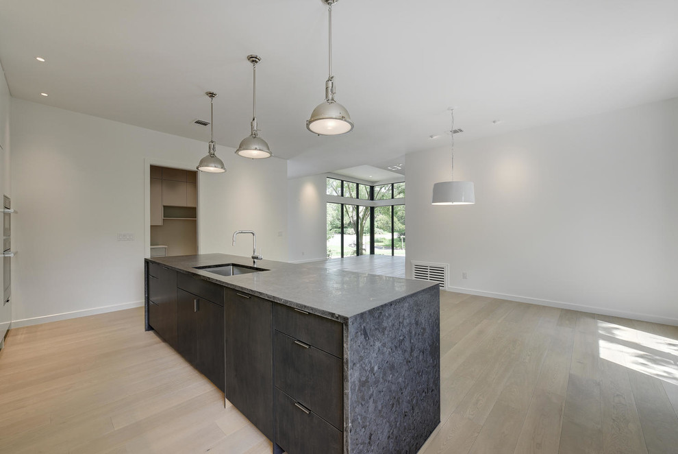Inspiration for a mid-sized transitional l-shaped light wood floor eat-in kitchen remodel in Austin with an undermount sink, flat-panel cabinets, black appliances, an island, gray cabinets and granite countertops