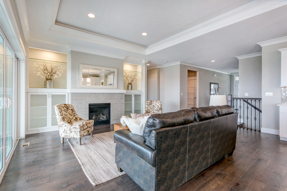 This is an example of a large transitional open concept living room in Seattle with grey walls, medium hardwood floors, a standard fireplace, a tile fireplace surround and a built-in media wall.