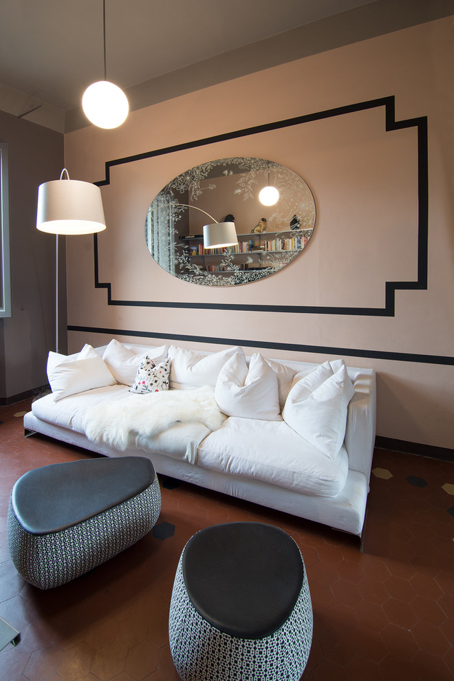Small transitional enclosed family room in Milan with a library, pink walls, terra-cotta floors and a wall-mounted tv.