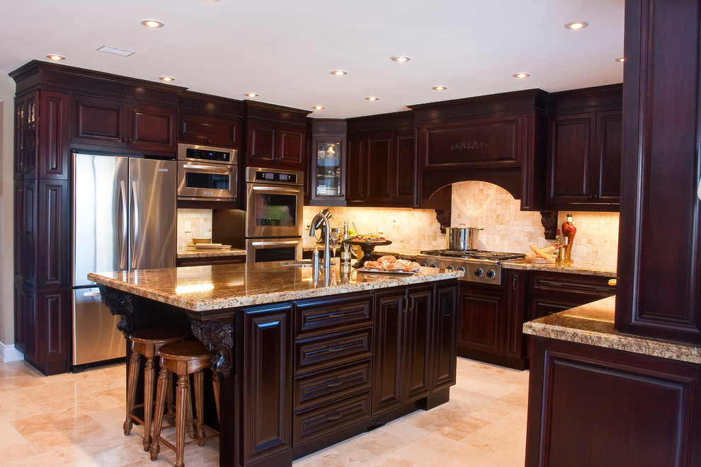 This is an example of a traditional u-shaped eat-in kitchen in Toronto with an undermount sink, raised-panel cabinets, brown cabinets, stainless steel appliances and with island.
