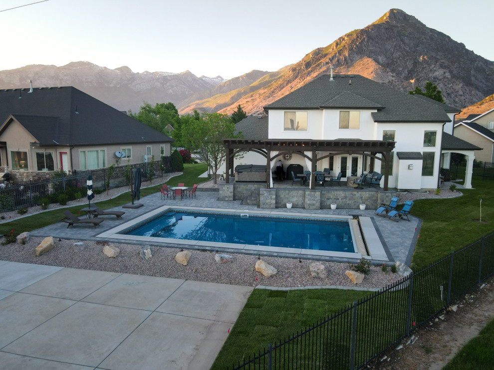 Ejemplo de piscina de estilo americano de tamaño medio a medida en patio trasero con paisajismo de piscina y adoquines de ladrillo