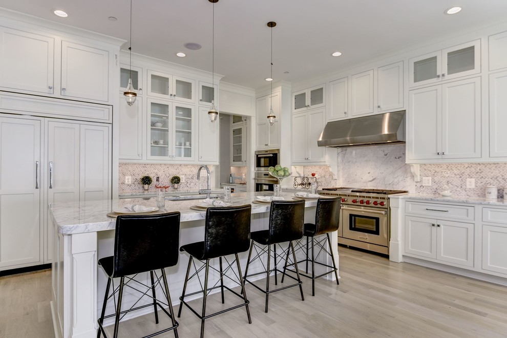 Inspiration for a large arts and crafts l-shaped open plan kitchen in DC Metro with an undermount sink, raised-panel cabinets, white cabinets, marble benchtops, white splashback, marble splashback, stainless steel appliances, light hardwood floors, with island and white floor.