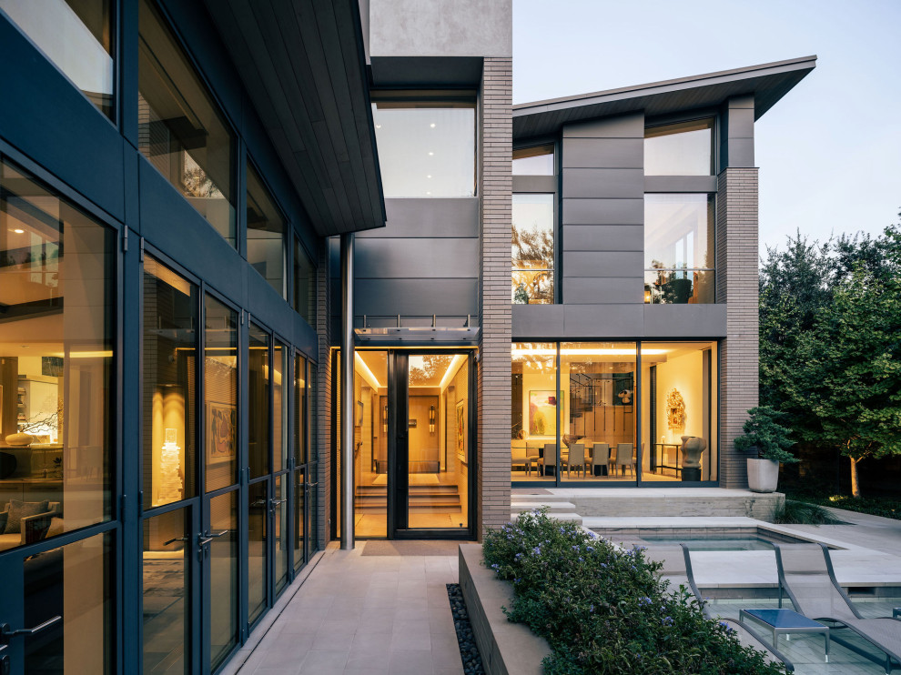 Inspiration for a large contemporary limestone floor, gray floor and brick wall front door remodel in Dallas with gray walls and a metal front door
