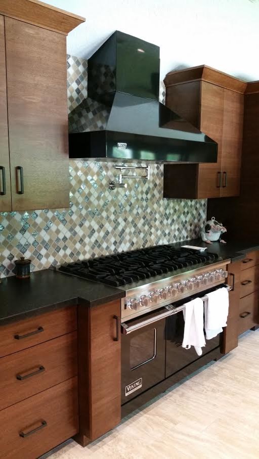 Mid-sized transitional light wood floor and beige floor open concept kitchen photo in Houston with flat-panel cabinets, medium tone wood cabinets, solid surface countertops, multicolored backsplash, glass tile backsplash, stainless steel appliances and no island