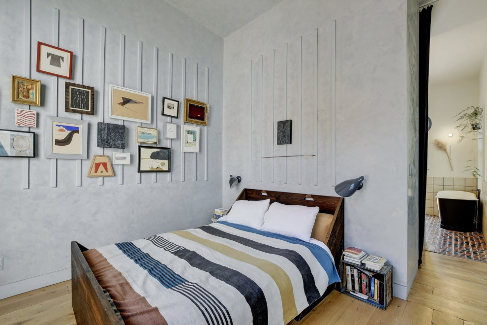 Diseño de dormitorio industrial con paredes grises, suelo de madera clara y suelo beige