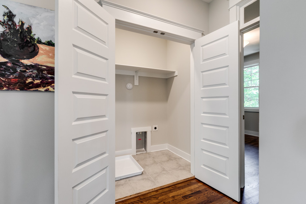 Inspiration for a mid-sized arts and crafts single-wall dedicated laundry room in Richmond with grey walls, medium hardwood floors, a side-by-side washer and dryer and brown floor.